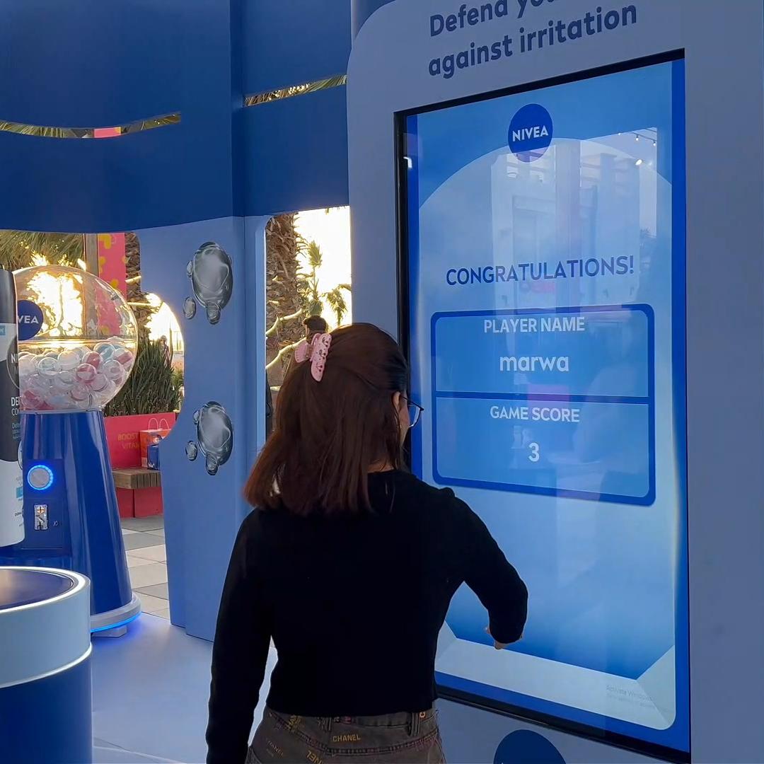 Guests playing the interactive Catch and Dodge game at a Niveae event in Dubai. Custom branded screen with data capture for exhibition marketing